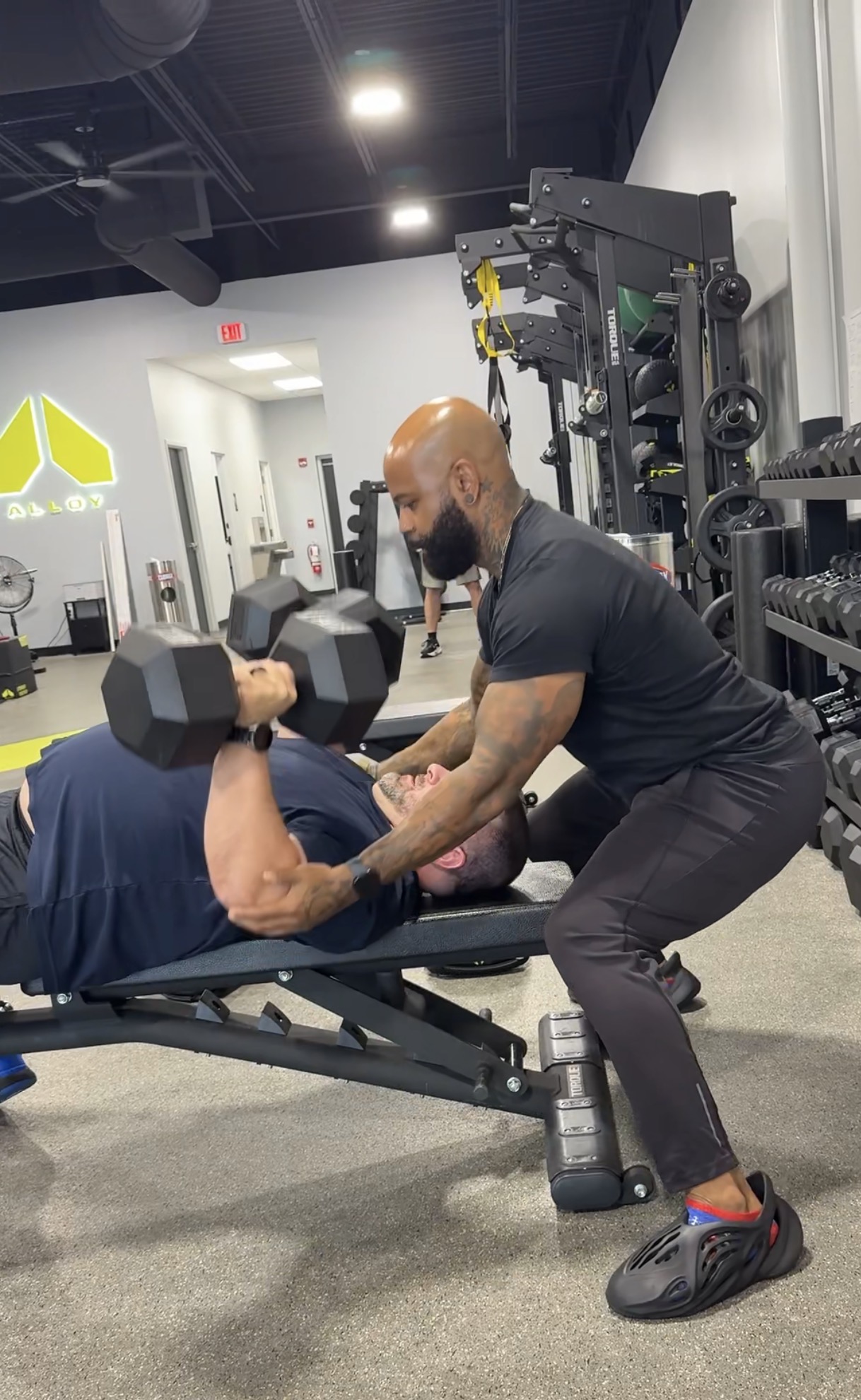Mt. Juliet coach supporting a member during a dumbbell bench press